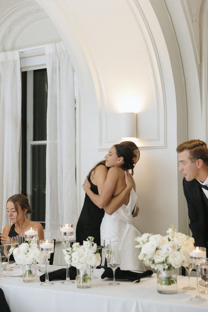 Bride wearing Mitchell wedding dress hugs her bridesmaid