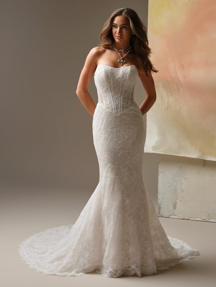 Ariadne strapless sheath wedding dress featuring allover Chantilly lace, a clean cat-eye neckline, and a softly fitted silhouette with an illusion lace train.