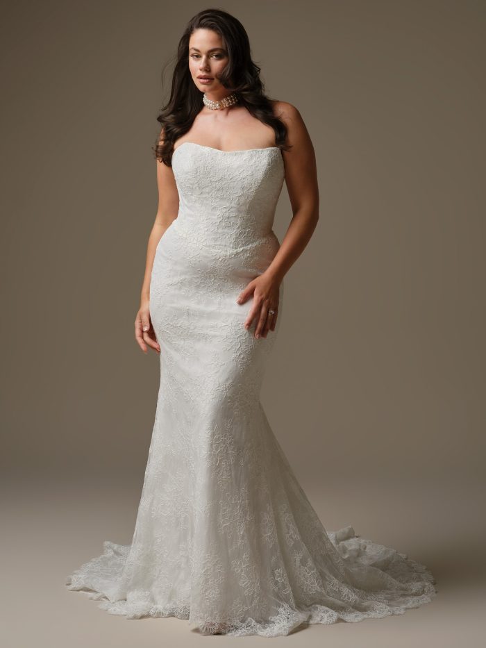 Ariadne sheath wedding dress featuring unembellished Chantilly allover lace, a strapless cat eye neckline, and an extended illusion lace train.