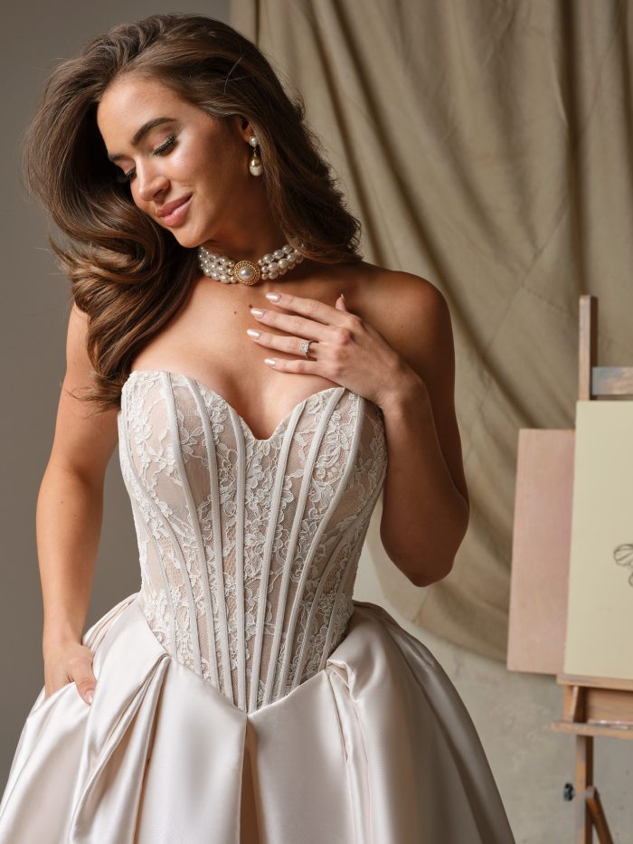 Close-up of Ashland by Maggie Sottero, featuring a sheer lace corset bodice with visible boning and sweetheart neckline paired with a luxurious satin skirt.