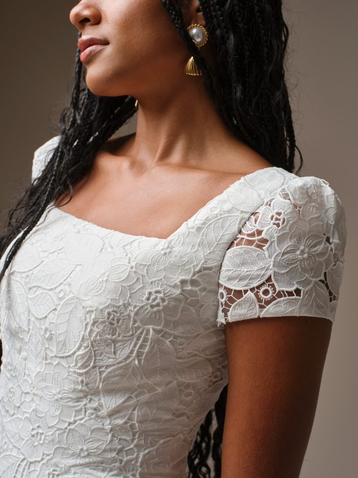 Close-up of the Dakota Leigh gown by Maggie Sottero, highlighting the square neckline, short lace sleeves, and textured floral lace detailing.
