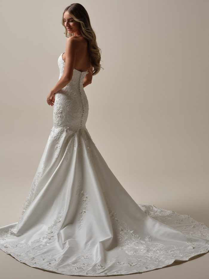 Back view of Delanie by Maggie Sottero strapless fit-and-flare wedding dress with a corset-style bodice, lace detailing, and a flowing lace-trimmed train.