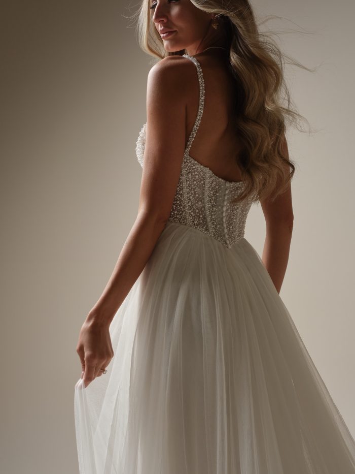Back view of the Gretchen gown showing the pearl-beaded bodice, delicate spaghetti straps, and flowy tulle skirt that moves gracefully for a soft, romantic bridal look.