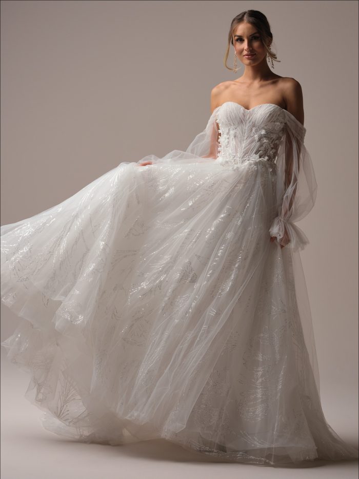 Bride wearing a sparkly A-line wedding dress with long illusion sleeves