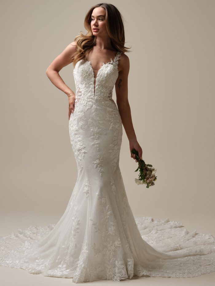 Bride wearing the Keegan fit-and-flare wedding dress featuring beaded and sequin lace motifs over glitter tulle, a plunging illusion V-neckline, and a soft lace train for a glamorous, figure-hugging look.