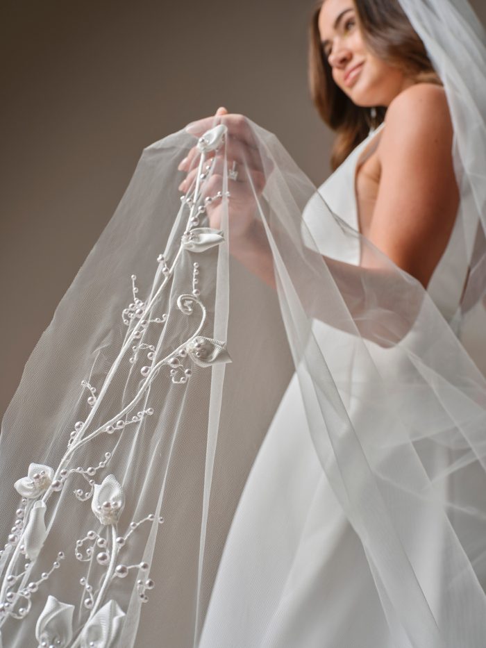 Close-up of the Lawrence veil by Maggie Sottero, highlighting the intricate 3D floral details and pearl accents held by the bride.