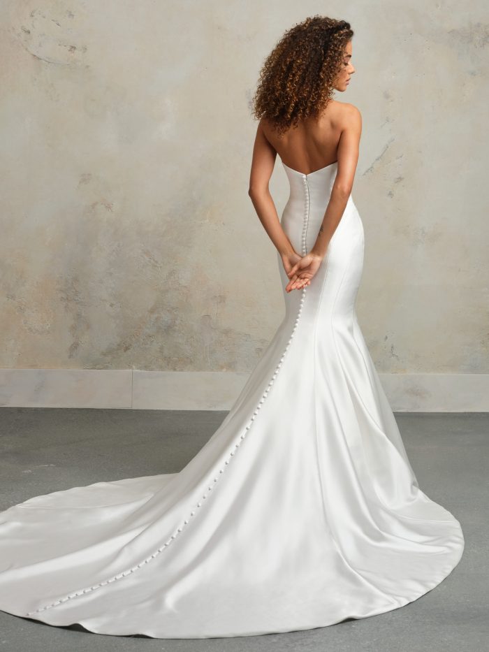 Back view of strapless satin fit-and-flare wedding dress featuring covered buttons down the train, minimalist design, and elegant curve-hugging silhouette