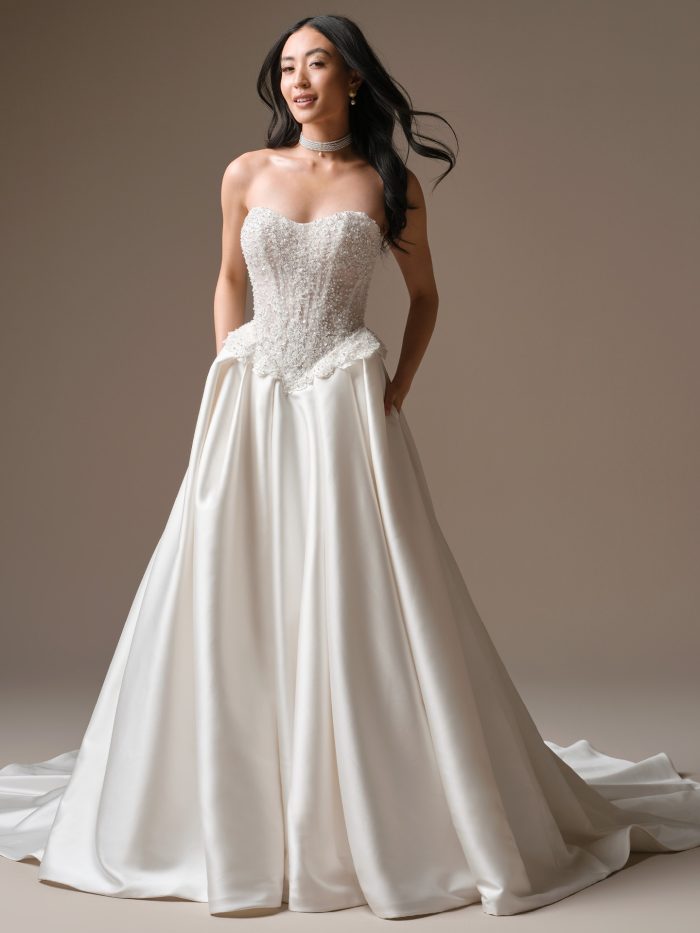 Front view of Maggie Sottero London ballgown wedding dress featuring a beaded lace corset bodice, sweetheart neckline, and full Mikado skirt with pockets.