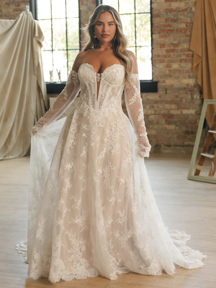 Bride wearing a romantic A-line lace wedding dress featuring a strapless sweetheart neckline, illusion corset bodice, and detachable off-the-shoulder sleeves. The gown shimmers with sequin lace appliqués and a soft chapel train, creating an effortlessly elegant look.