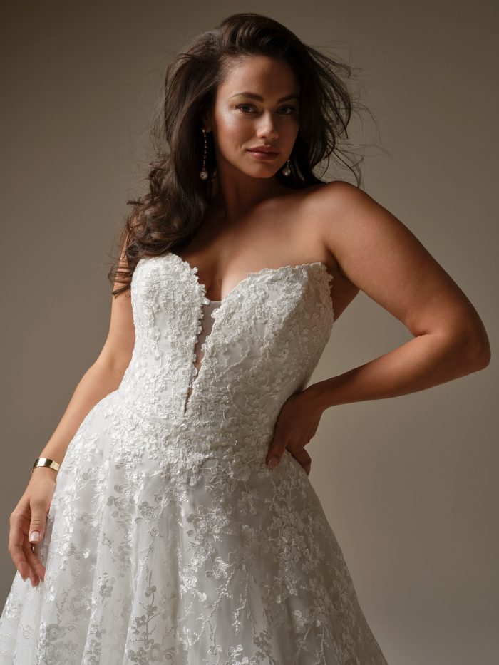 Close-up of Memphis by Maggie Sottero featuring a sheer lace bodice with exposed boning, plunging illusion neckline, and shimmering lace over tulle.