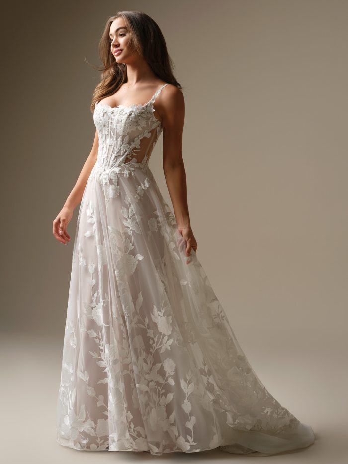 Full view of the Natalie Marie wedding dress by Maggie Sottero with allover unembellished lace, sheer side cut-outs, A-line silhouette, and illusion lace train