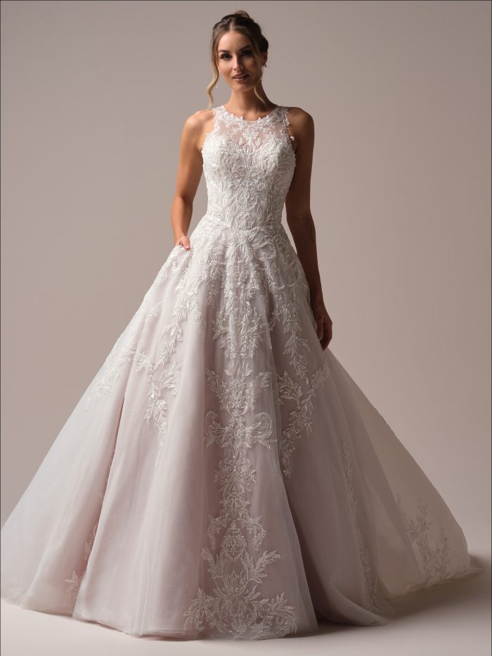Bride wearing Nina by Maggie Sottero, a romantic A-line wedding dress with illusion halter neckline, fully beaded lace bodice, and layered tulle skirt with intricate lace appliqués.