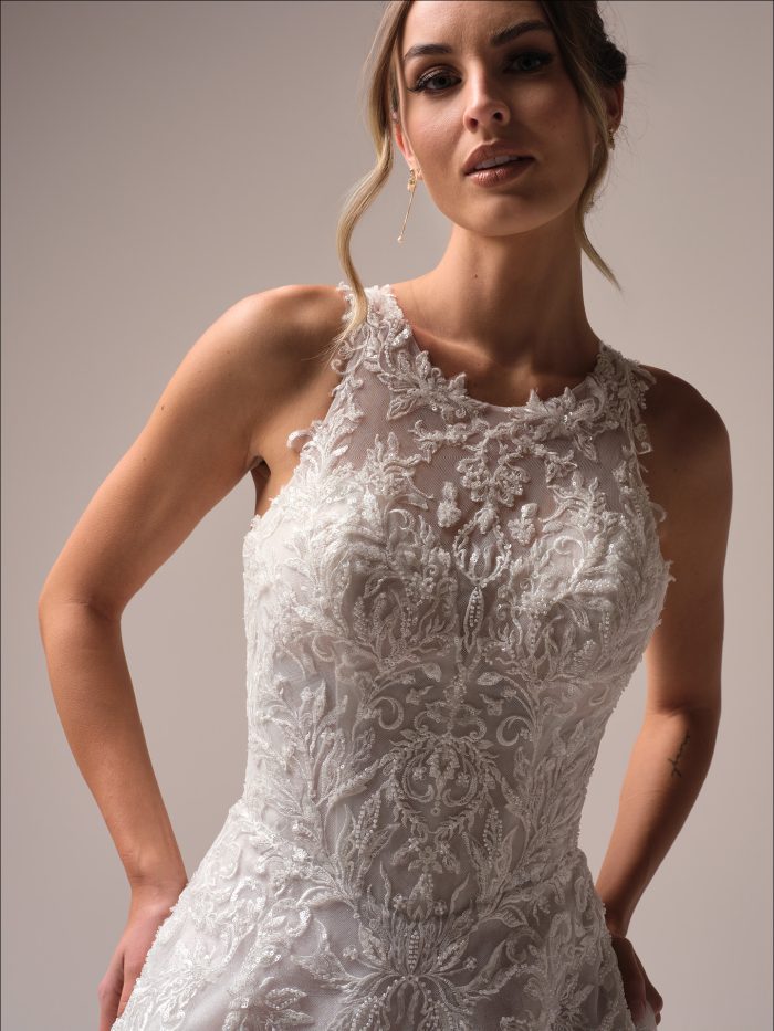 Close-up of Nina by Maggie Sottero showing detailed beaded lace bodice, illusion halter neckline, and intricate embroidery for a princess-inspired look.