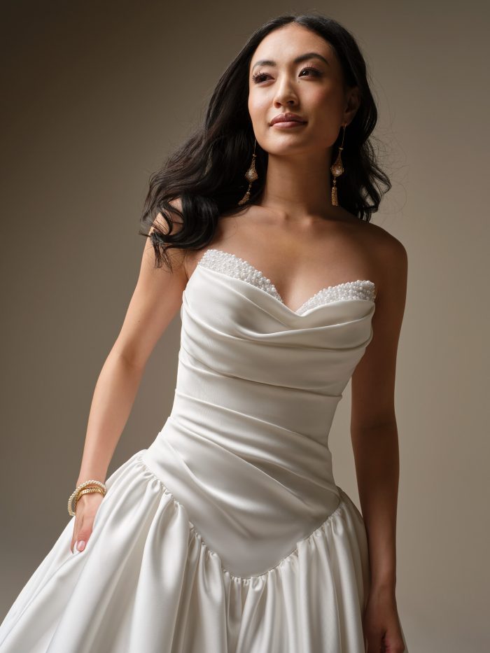 Close up of the Pasadena wedding dress showing the draped satin bodice, sweetheart neckline with bead and pearl details, and exaggerated basque waistline.