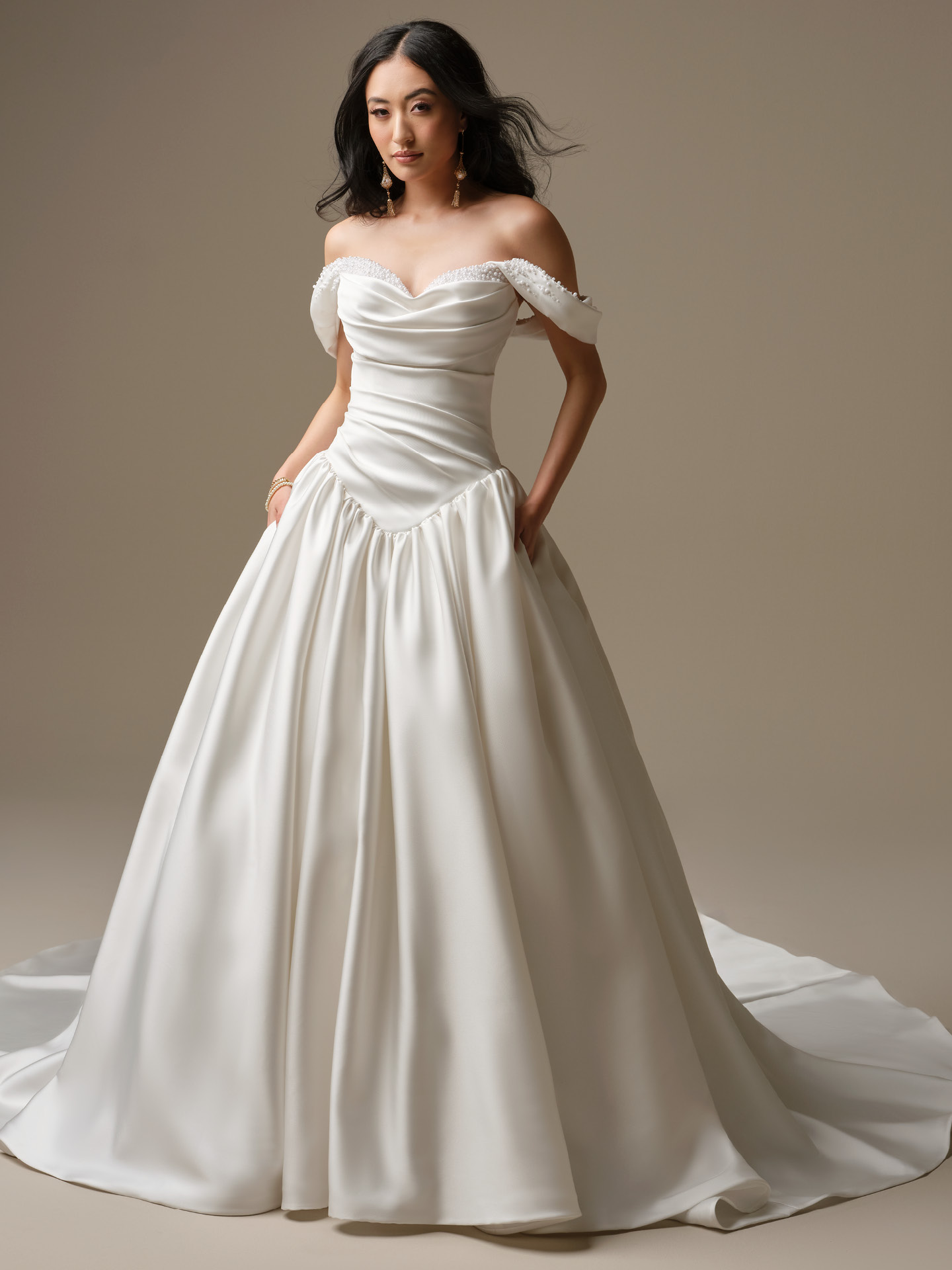 Pasadena satin ballgown wedding dress with off-the-shoulder pearl-trimmed neckline, draped bodice, Basque waist, and full princess skirt with train.