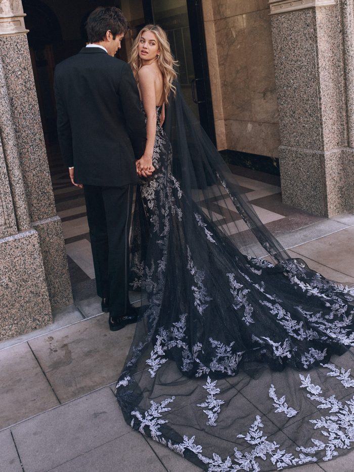 Bride wearing Peony by Maggie Sottero, a strapless black fit-and-flare wedding dress with sweetheart neckline, floral lace embroidery, and dramatic chapel-length train.