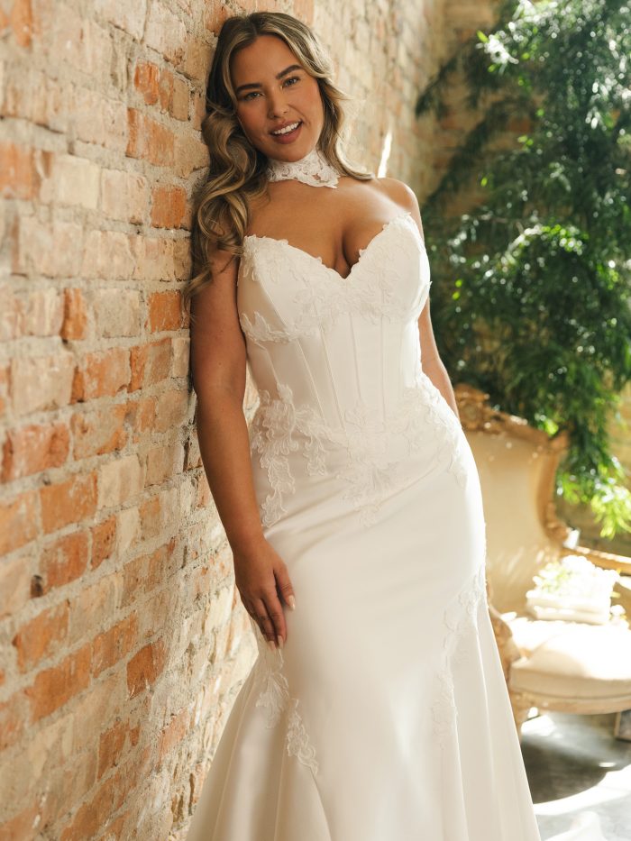 Bride in the Serafina Lane gown showing the curve-hugging silhouette, lace-accented bodice with exposed boning, and detachable lace high-neck detail for a couture-inspired look.