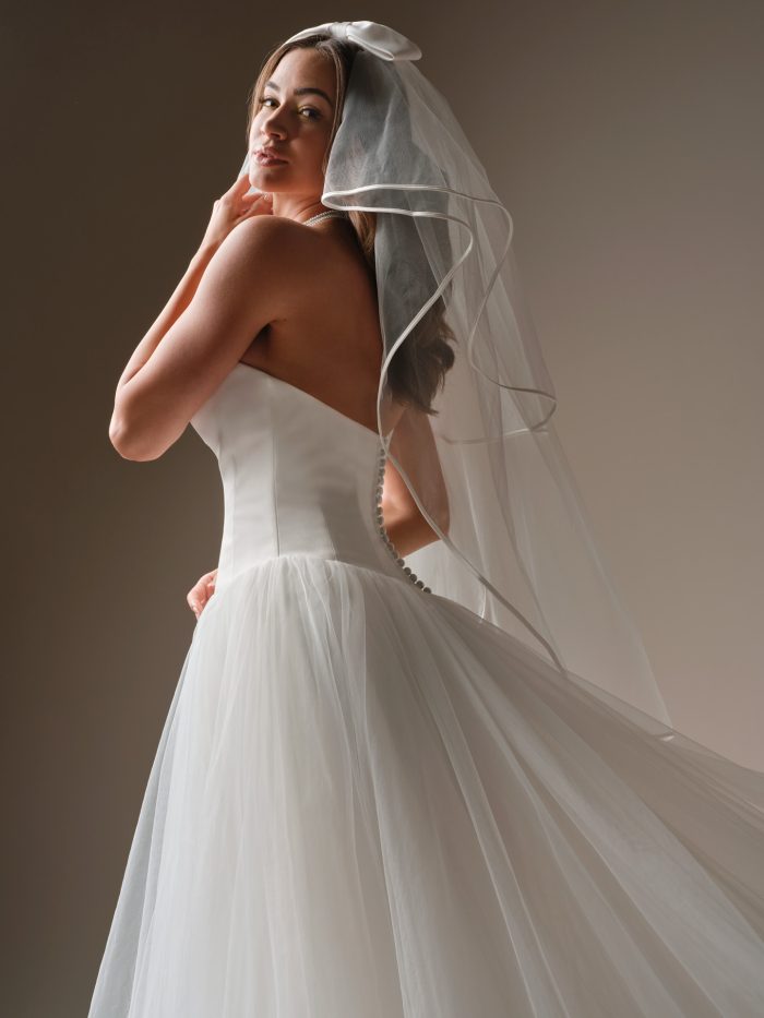 Maggie Sottero Shirley strapless tulle ballgown wedding dress featuring corset back and flowing skirt with veil
