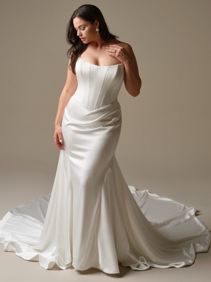 Sinclaire by Maggie Sottero fit-and-flare wedding dress in Ganavi stretch satin with a basque waist, strapless neckline, and sculpting corset bodice