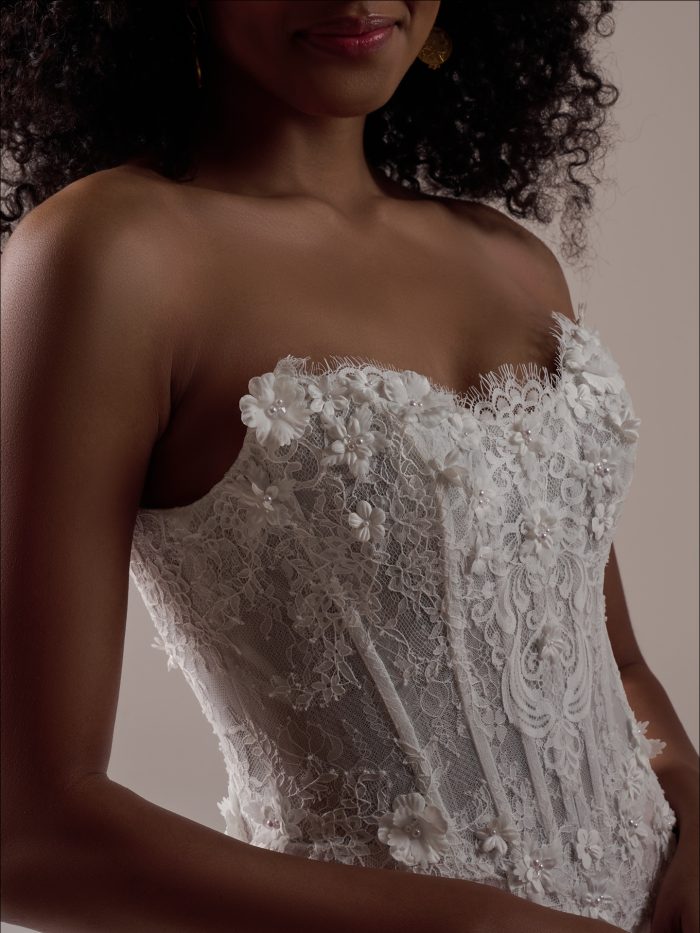 Close up of the Takera wedding dress showing the dimensional floral appliqués, lace bodice detailing, and scalloped neckline.