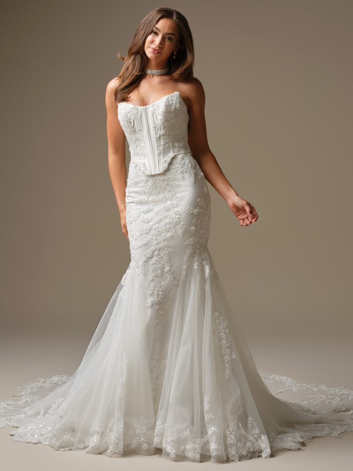 Front view of Maggie Sottero Wyntelle fit-and-flare wedding dress featuring a strapless exposed boning bodice, beaded lace motifs, and a flowing tulle skirt with chapel-length train.
