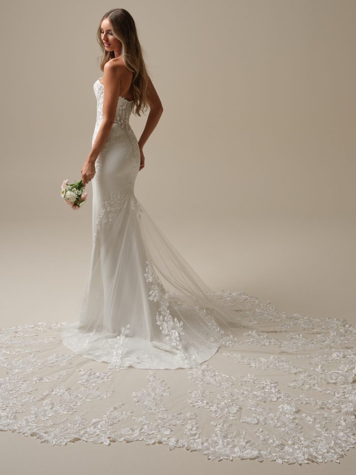Back view of the Yara sheath wedding dress by Maggie Sottero, showcasing the sleek crepe silhouette, floral lace detailing, and extended lace train flowing behind the bride.