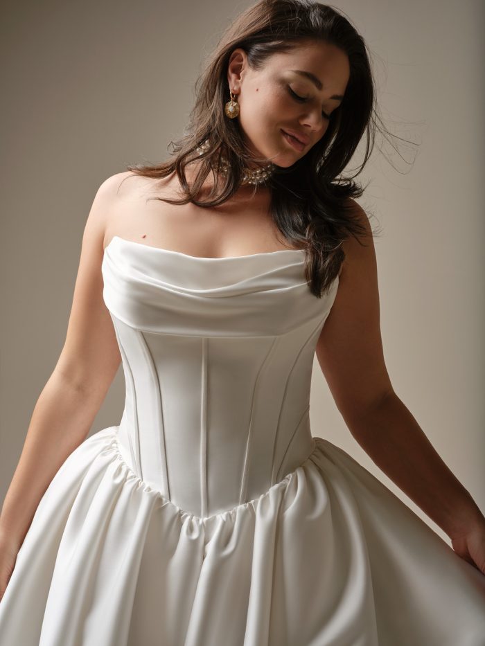 Close-up of the Yuma wedding dress by Maggie Sottero showing a draped cowl neckline, structured boning, and sculpted basque waistline in Felicity Mikado