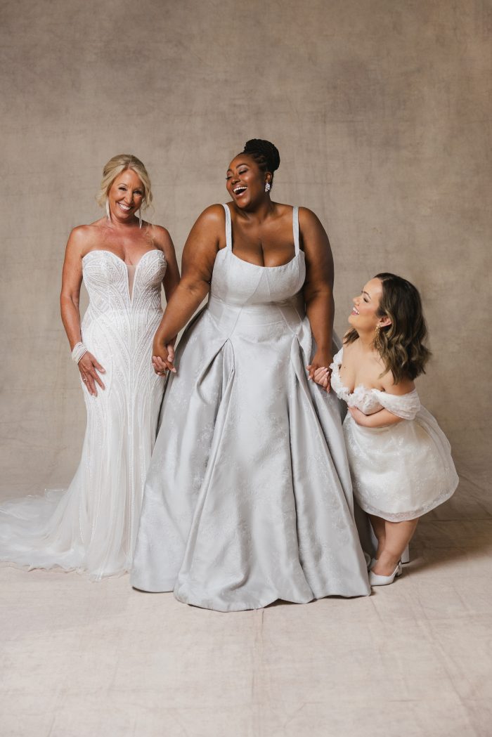 Three brides together wearing a variety of wedding dress types
