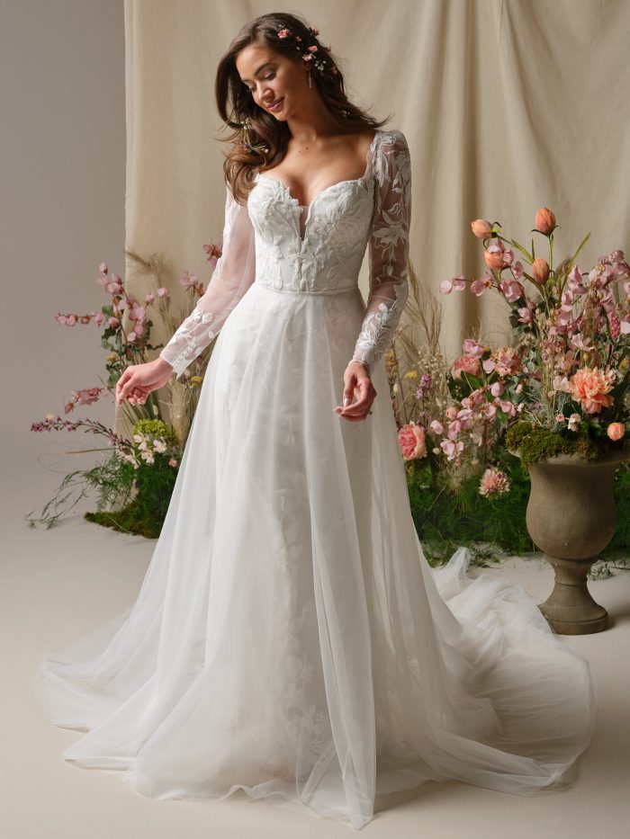 Bride wearing the Aubra gown with the detachable tulle overskirt, showcasing the long illusion lace sleeves, floral bodice, and added soft A-line skirt for extra volume.