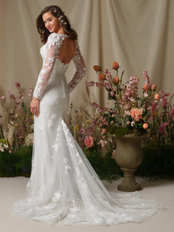 Back view of the Aubra wedding dress showing the keyhole back, long illusion lace sleeves, covered button over zipper closure, and extended illusion lace train.