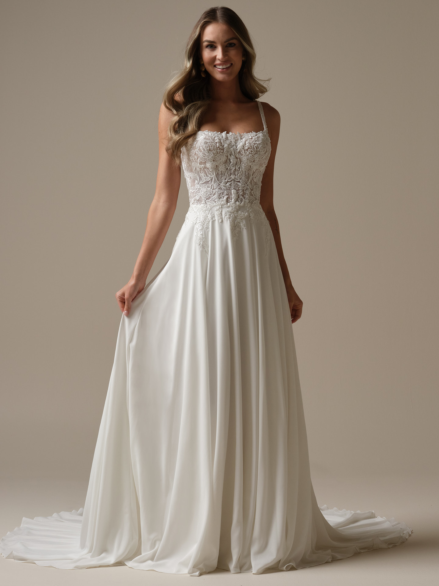 Bride wearing Avery by Rebecca Ingram, an A-line wedding dress with lace bodice, delicate spaghetti straps, and flowing chiffon skirt with soft train.