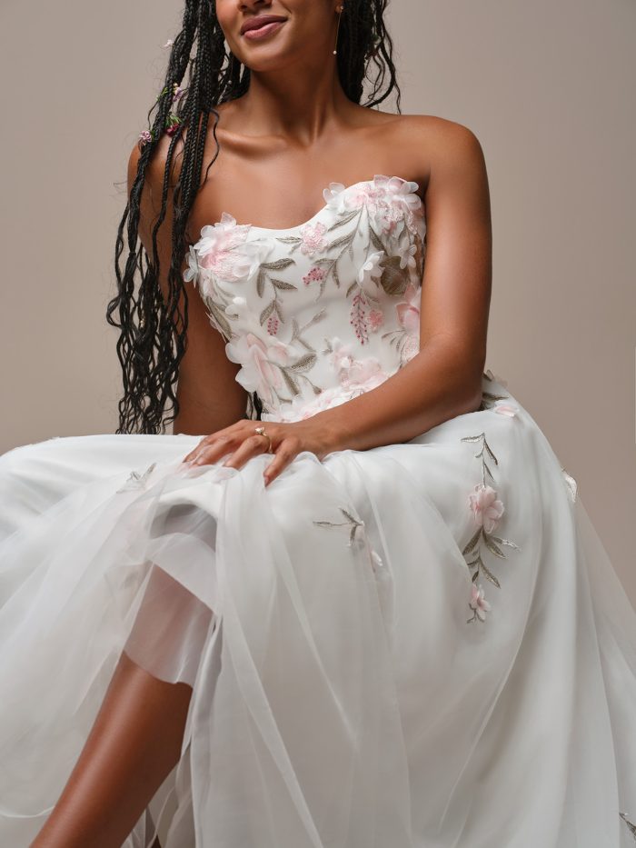 Close-up of the Rebecca Ingram Blossom A-line wedding dress bodice with strapless sweetheart neckline, dimensional blush floral appliqués, and delicate embroidered leaf accents over soft tulle.