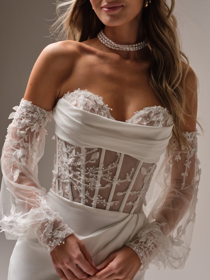 Close up of the Bree gown highlighting the sheer embroidered corset, 3D lace details, and detachable beaded tulle sleeves paired with a pearl choker.