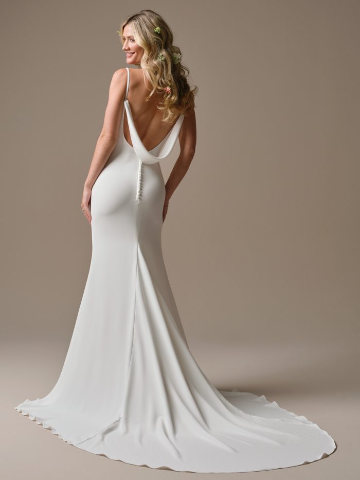 Close up of the Brenda sheath wedding dress featuring the cowl neckline, thin straps, and back ribbon detail, shown on a smiling bride with soft waves.