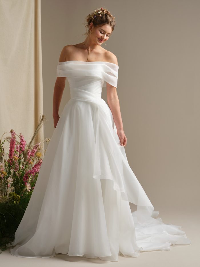 Off-the-shoulder Rebecca Ingram Dezi wedding dress with draped chiffon bodice and airy A-line skirt