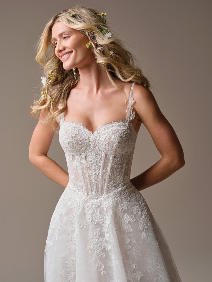 Close-up of the Esmeralda wedding dress by Rebecca Ingram showing an illusion lace bodice with exposed boning, basque waist detail, and lace spaghetti straps