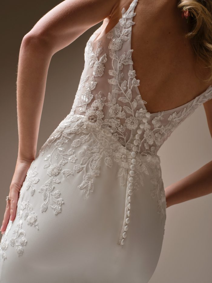 Close up of the Holly gown’s low back and sheer floral lace bodice, showing the button closure and embroidered appliqués trailing onto the skirt.