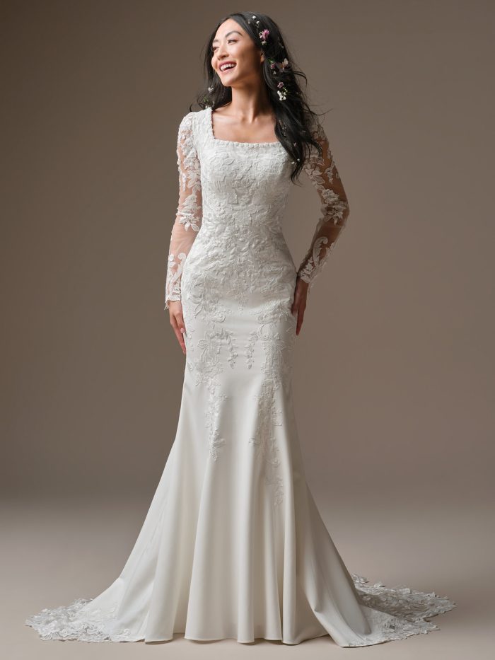Larissa Leigh by Rebecca Ingram, Sherwood crepe sheath wedding dress with unembellished lace overlay, modest square neckline, long illusion lace sleeves, and extended lace train.