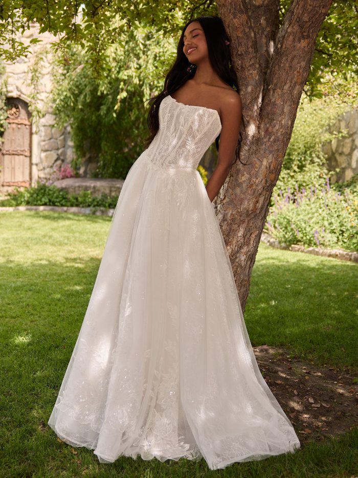 Bride wearing an ethereal strapless ballgown wedding dress with an illusion lace bodice and full tulle skirt. The gown features delicate leaf embroidery and subtle shimmer, creating a dreamy and romantic garden bridal look.