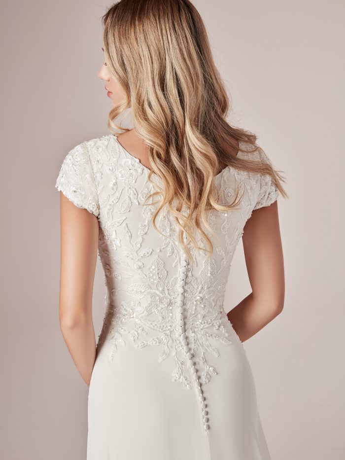 Model Wearing Cap-Sleeve Modest Sheath Wedding Dress Called Mercy Leigh by Rebecca Ingram