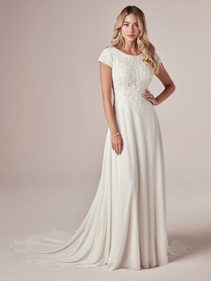 Model Wearing Cap-Sleeve Modest Sheath Wedding Dress Called Mercy Leigh by Rebecca Ingram