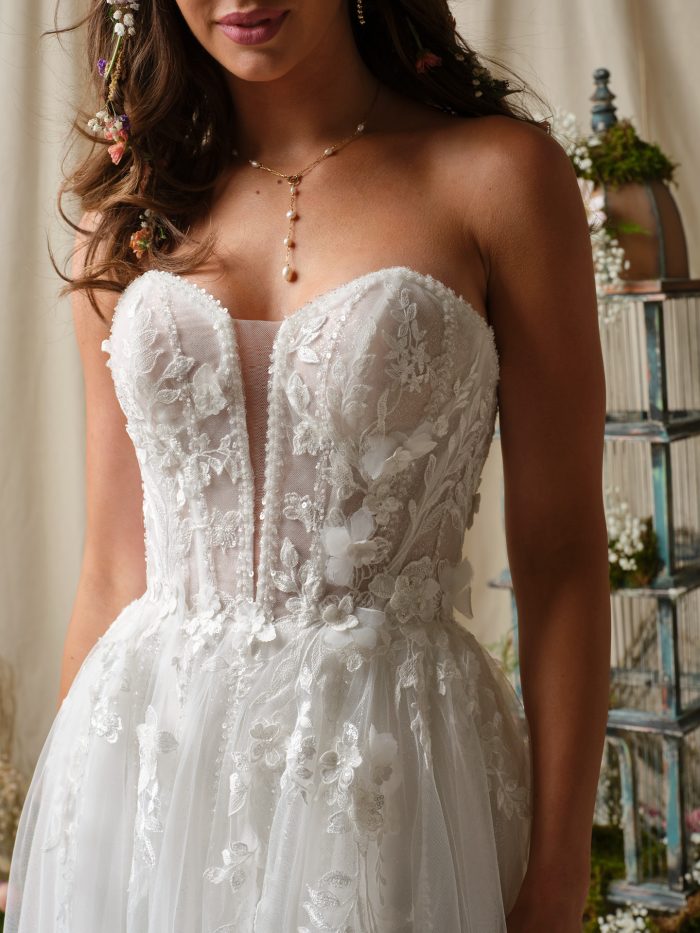 Nora A-line wedding dress with a strapless sweetheart bodice, 3D floral lace detailing, and sheer textured corset captured in a close up studio shot.