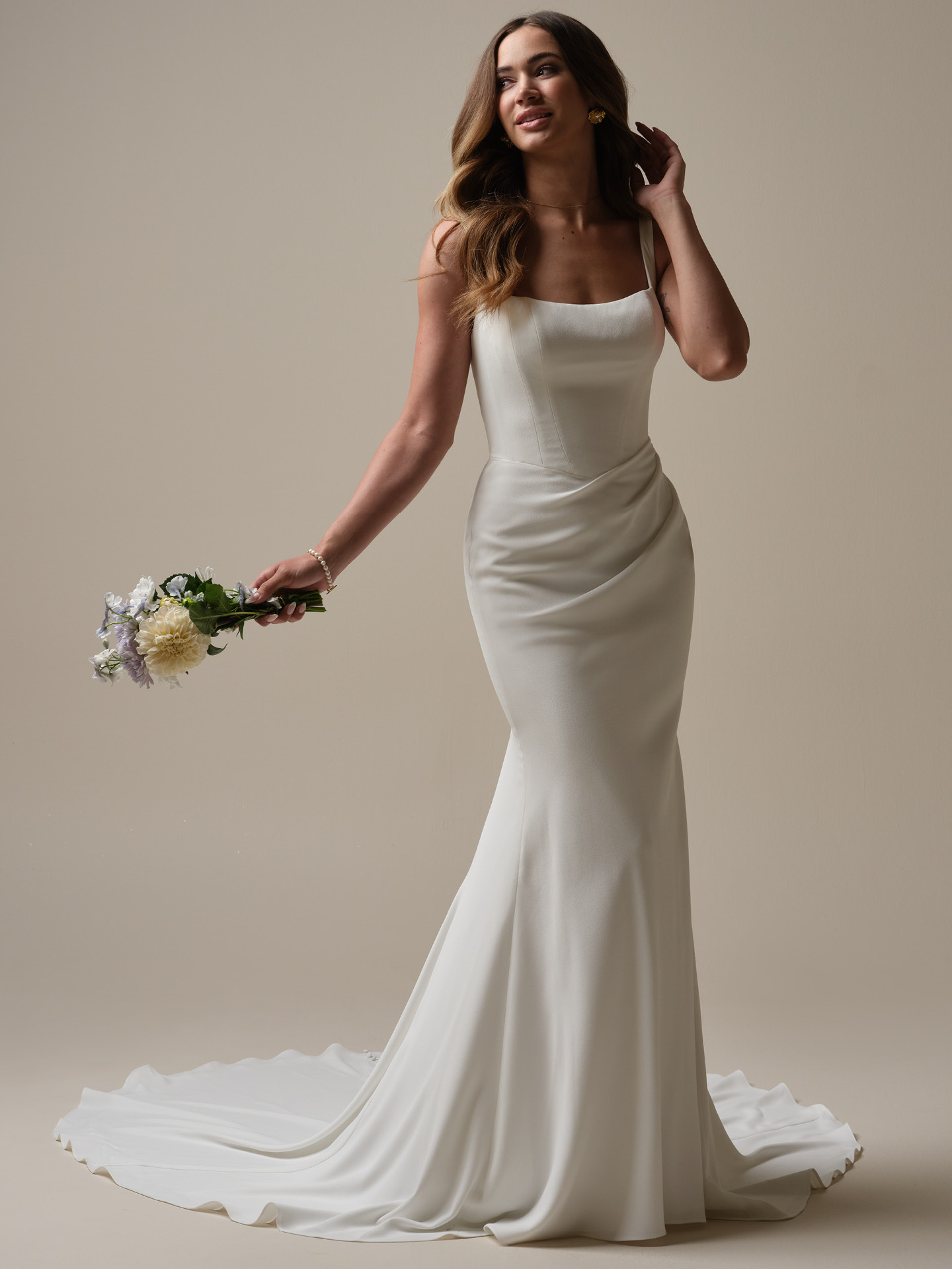 Bride wearing Olivianna Lane by Rebecca Ingram, a minimalist mermaid wedding dress in crepe with square neckline, tank straps, and sculpted fitted silhouette.