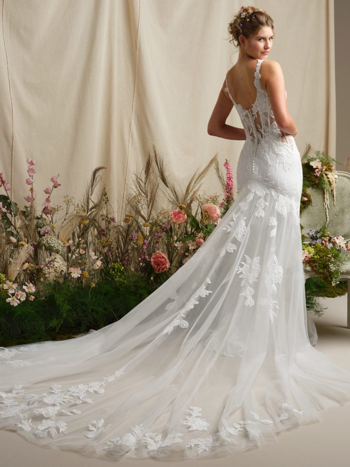 Back view of a fit-and-flare wedding dress featuring a V-back illusion lace bodice, lace tank straps, covered button closure, and an extended illusion lace train.