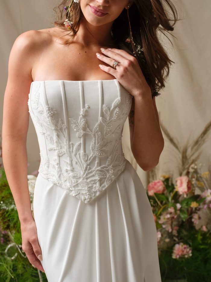 Close-up of Rebecca Ingram Terry wedding dress bodice with exposed boning, embroidered lace detailing, and pointed Basque waist.