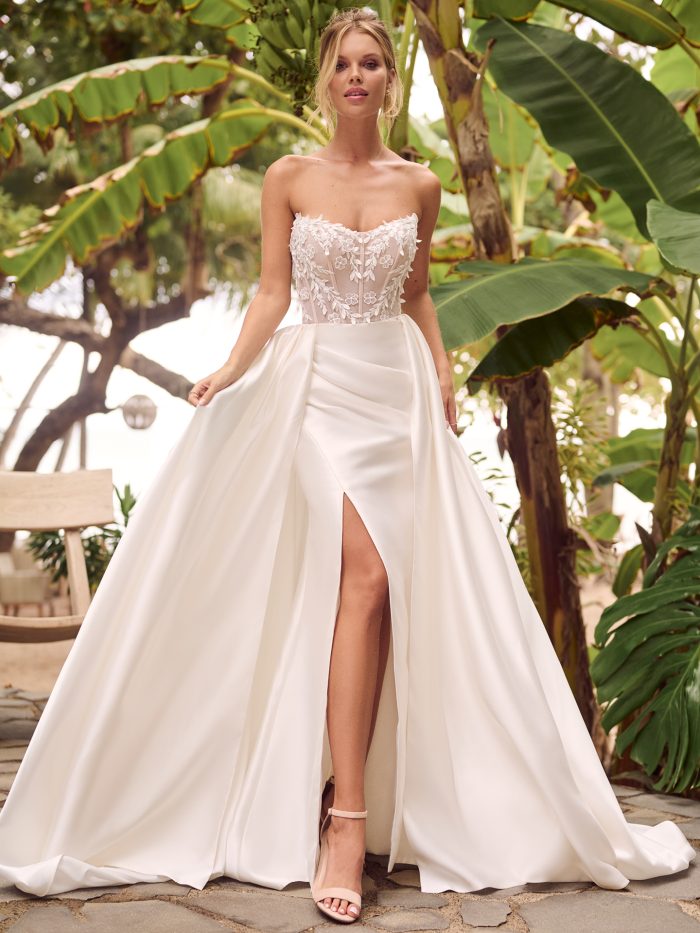 Strapless wedding dress with floral lace bodice and sweetheart neckline, paired with sleek Mikado A-line skirt featuring a thigh-high slit, styled in a tropical garden setting