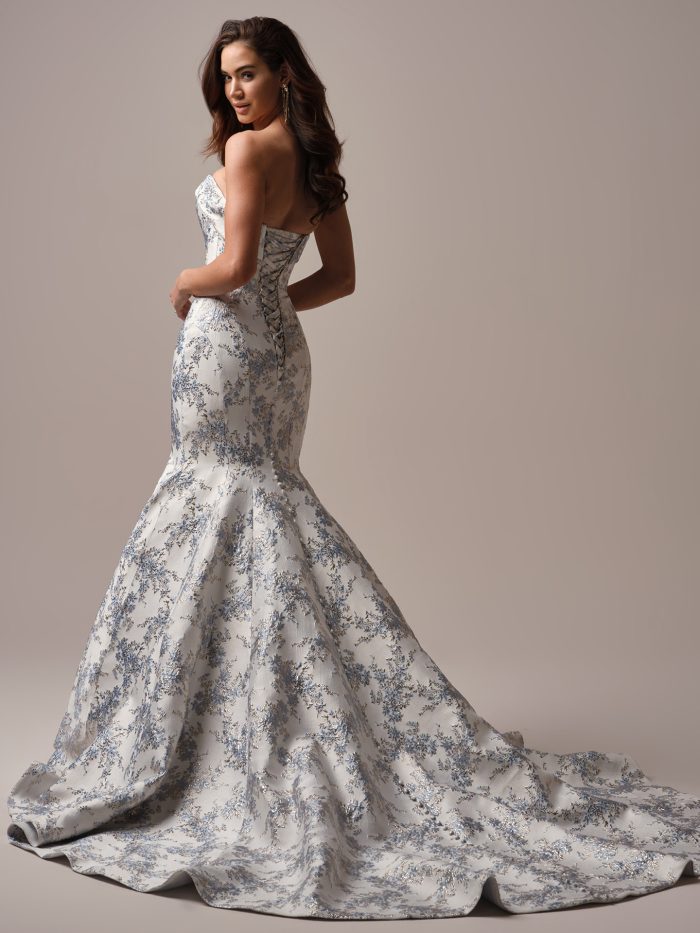Back view of the Sottero and Midgley Aberdeen Lane gown showing the lace-up corset closure, fitted jacquard silhouette, and extended train with elegant floral patterning.