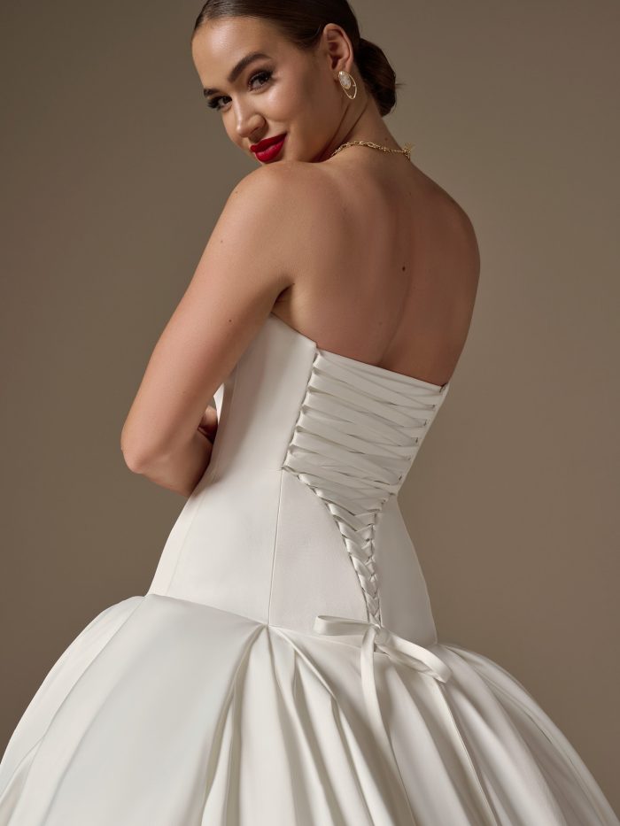 Back view of the Adair wedding dress by Sottero and Midgley highlighting the strapless neckline, lace-up corset back, and sculpted waist with a voluminous satin skirt.
