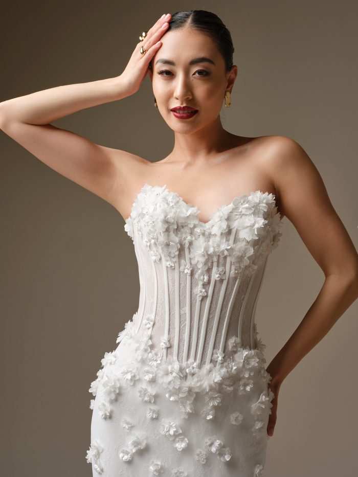 Close up of the Akari wedding dress showing the strapless sweetheart neckline, sheer bodice with exposed boning, and 3-D floral accents.