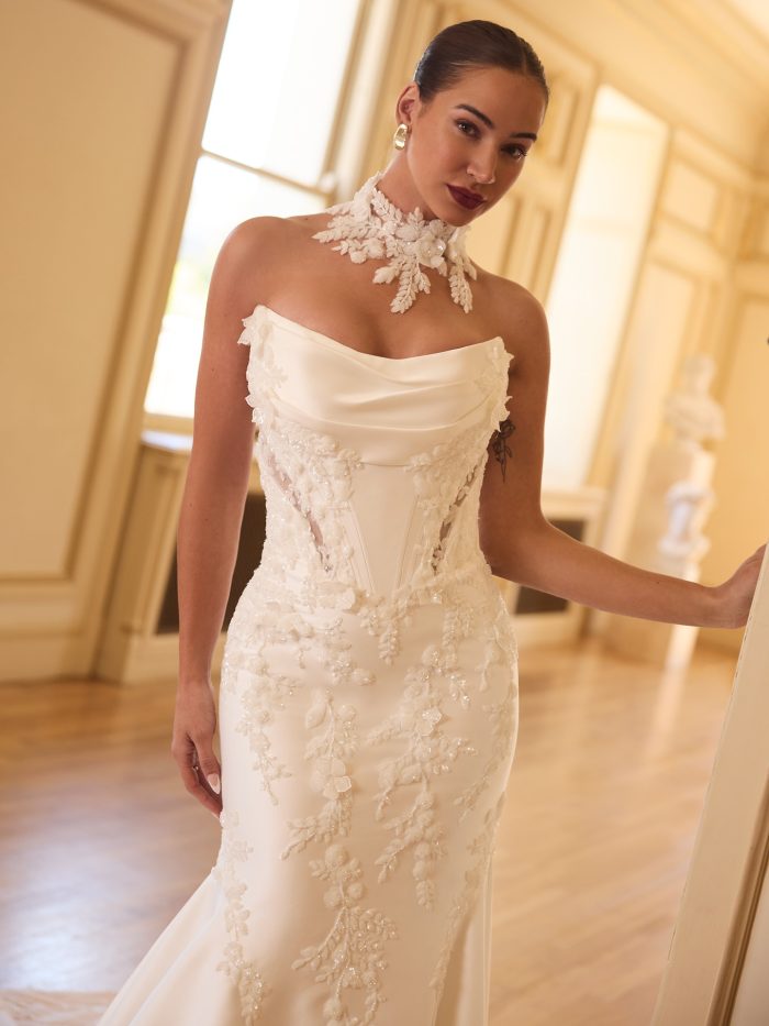 Close-up of the Burke fit and flare wedding dress showing the draped satin neckline, exposed corset-style bodice, and dimensional floral lace appliqués cascading down the silhouette.